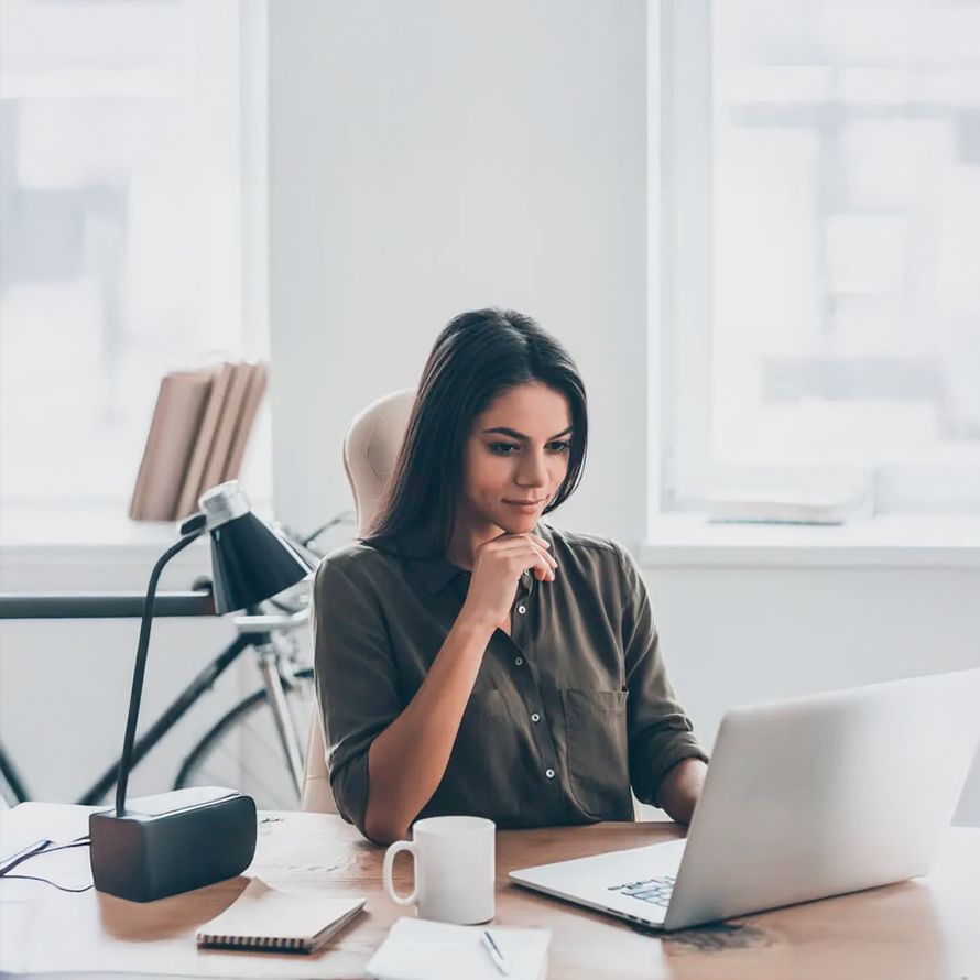 Chica reflexiona delante de un ordenador posilbles nombres nombres de dominios .com para su proyecto