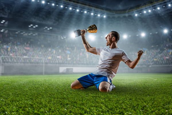 Jugador de fútbol con copa de campeón, destacando la pasión del deporte con dominios .futbol