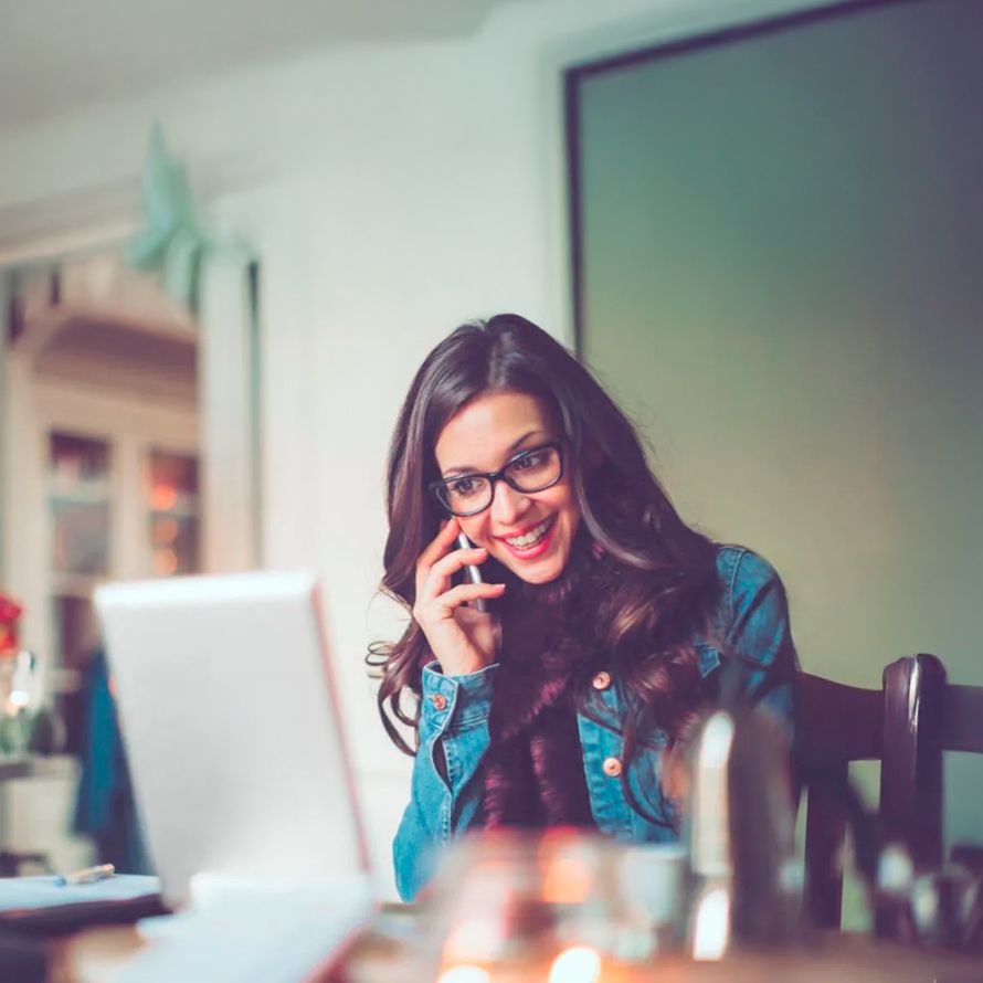 Chica hablando por el móvil y consultando un ordenador para registrar un dominio .info