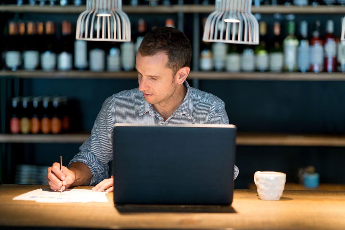 Chico haciendo, delante de su ordenador, una lista con los dominios .org que quiere registrar
