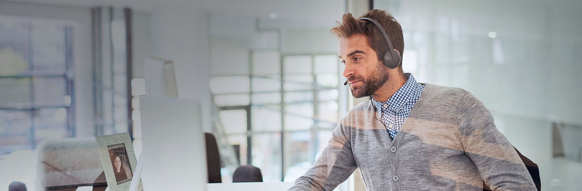 Agente de soporte con cascos y frente a un ordanador escuchando los requerimientos de tu proyecto