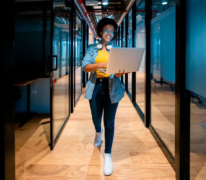 Chica caminando con su portátil por el centro de datos de Arsys