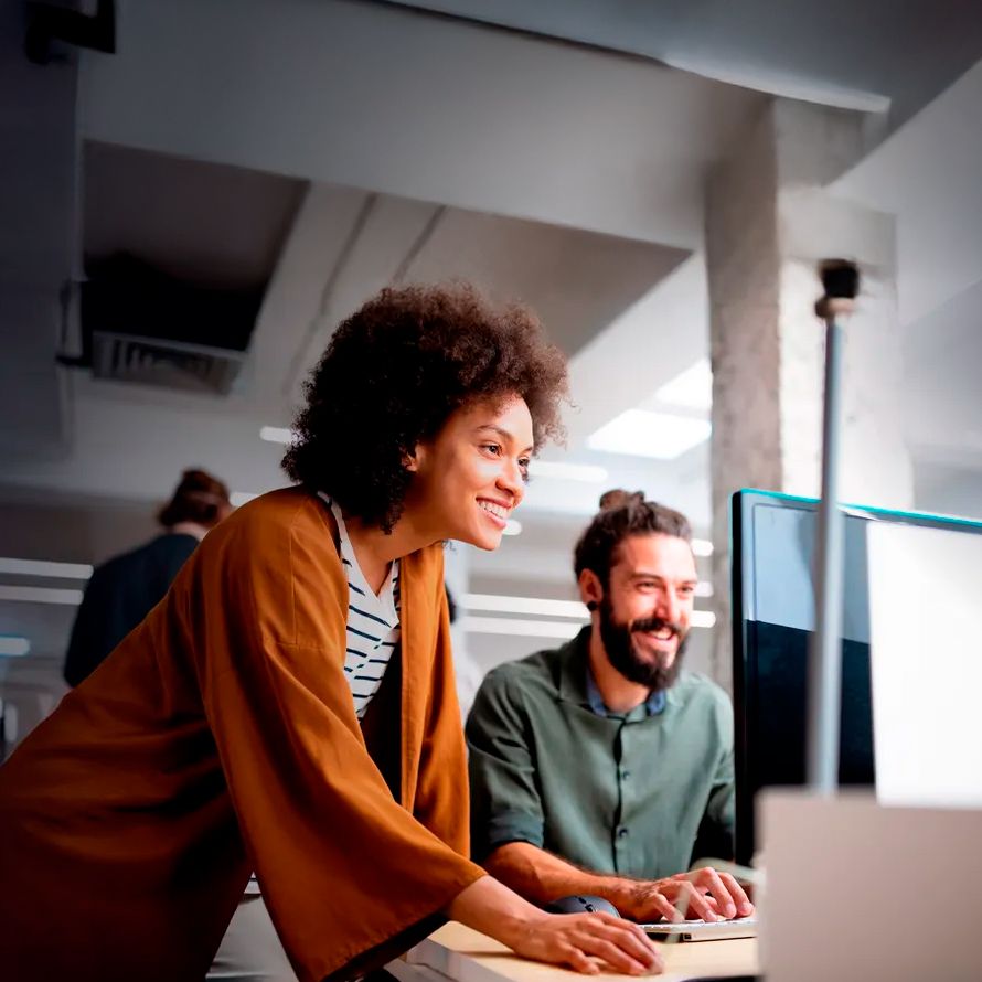 Dos compañeros trabajan contentos en un ordenador porque su web ha subido posiciones en los principales buscadores