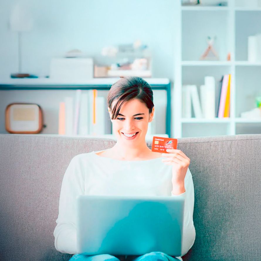 Chica sonríe con una tarjeta de crédido en la mano porque va a comprar en una tienda online con certificado SSL