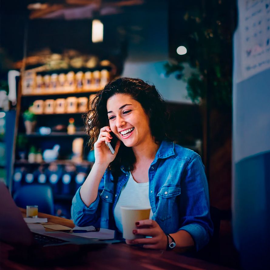 Chica hablando con teléfono muy contenta porque por fin puede crear su tienda online sin complicaciones