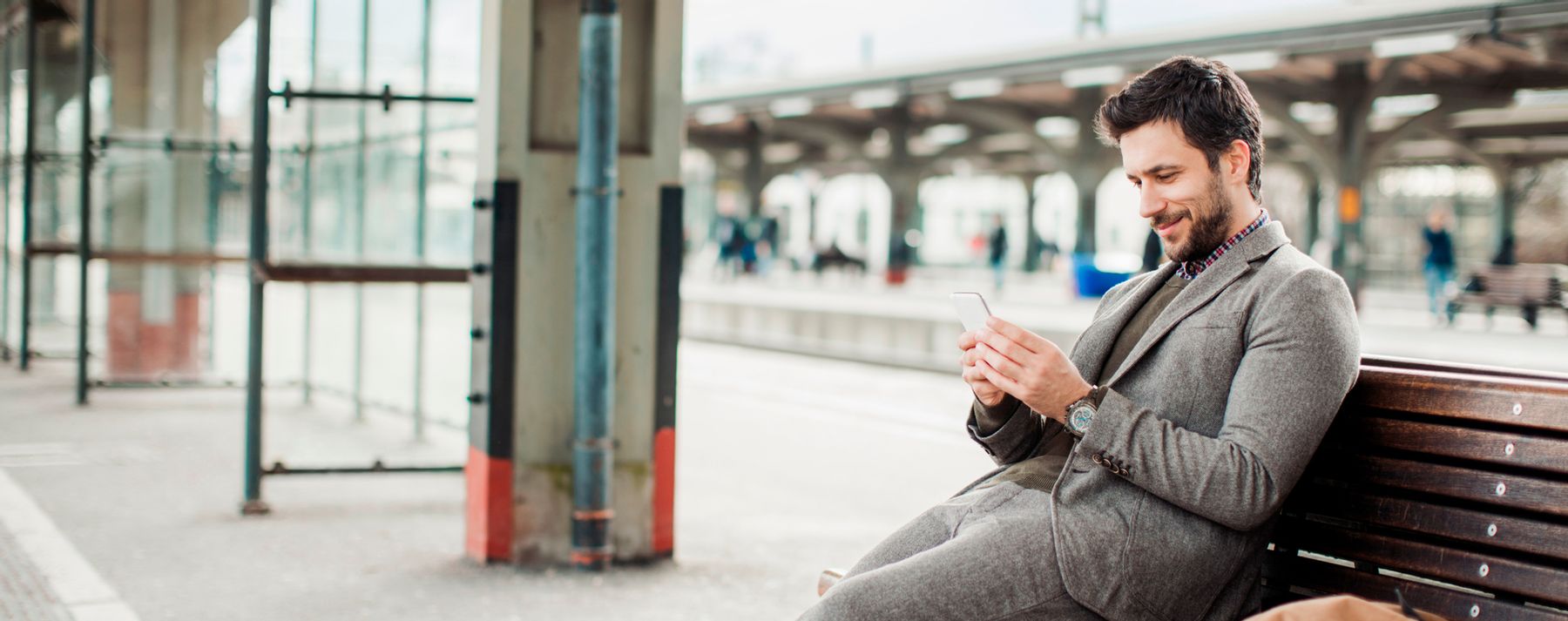 Chico sentado en un banco consulta su móvil para crear su código QR
